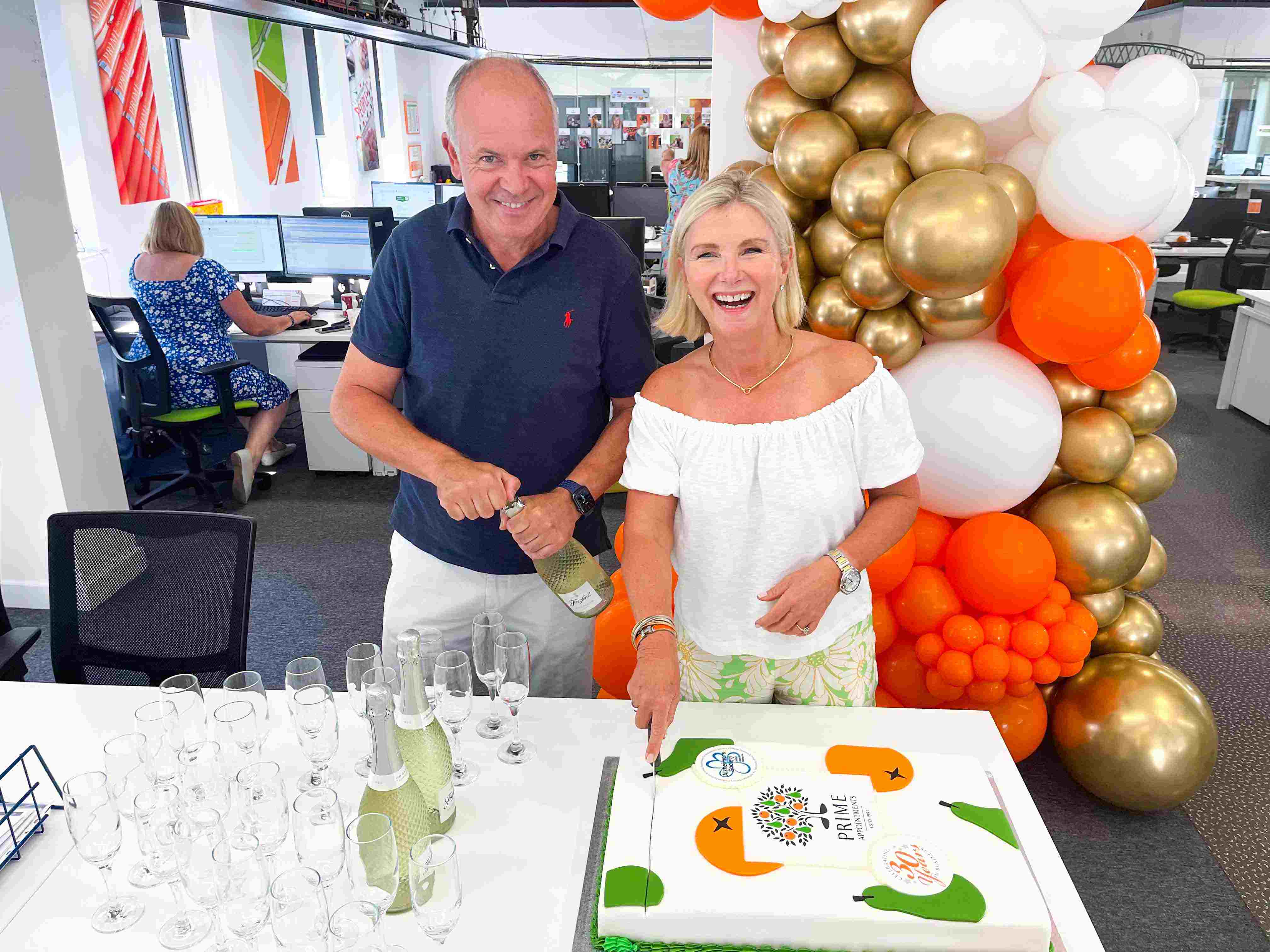 Robyn Holmes, MD & Peter Holmes, Director cutting cake at Prime Appointments, as they celebrate 30 years in business