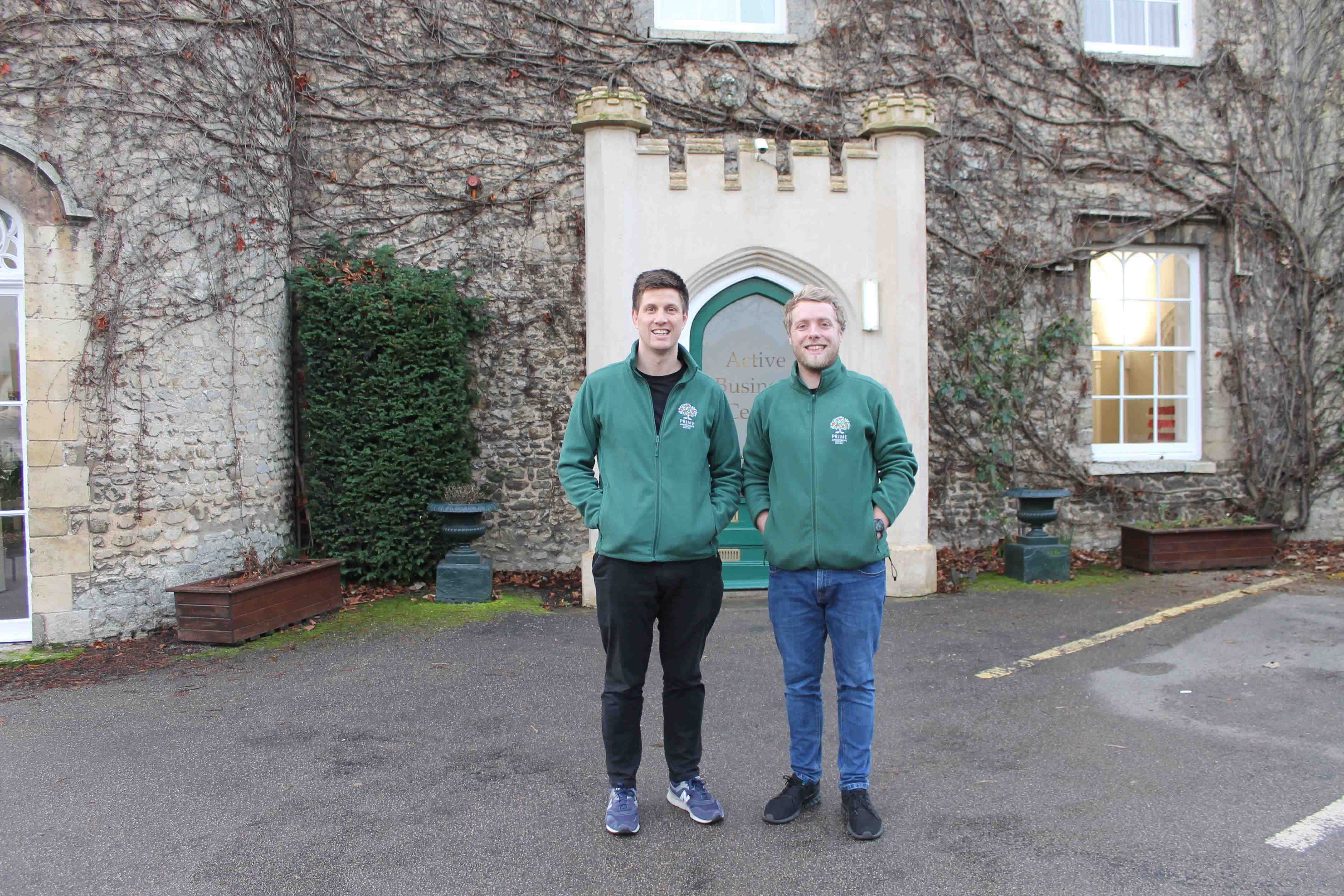 Jack O'Brien & Carl Bashford standing outside Bury St Edmunds office wearing green Prime Appointments fleeces