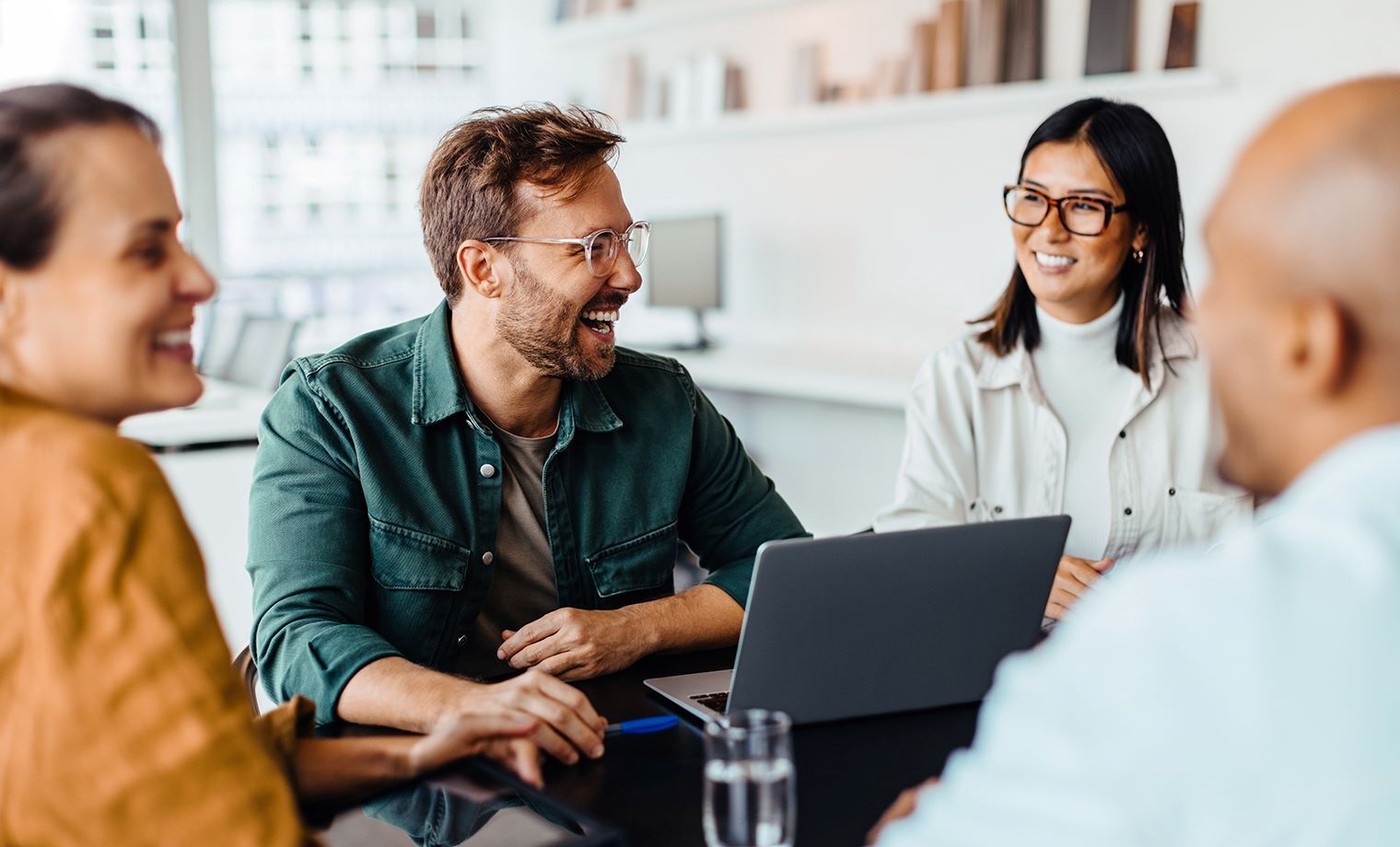 Header image, people laughing and smiling at the table with laptop