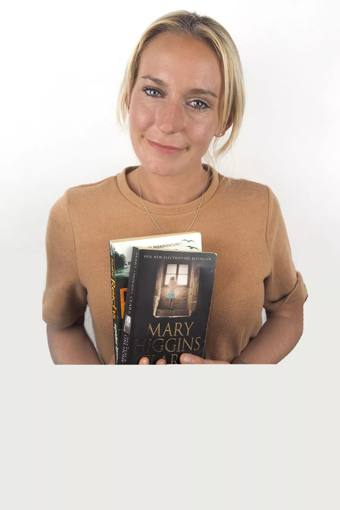 Nikita White (Recruitment Consultant) holding books in hand, wearing a mustard top, photo taken with white background 2