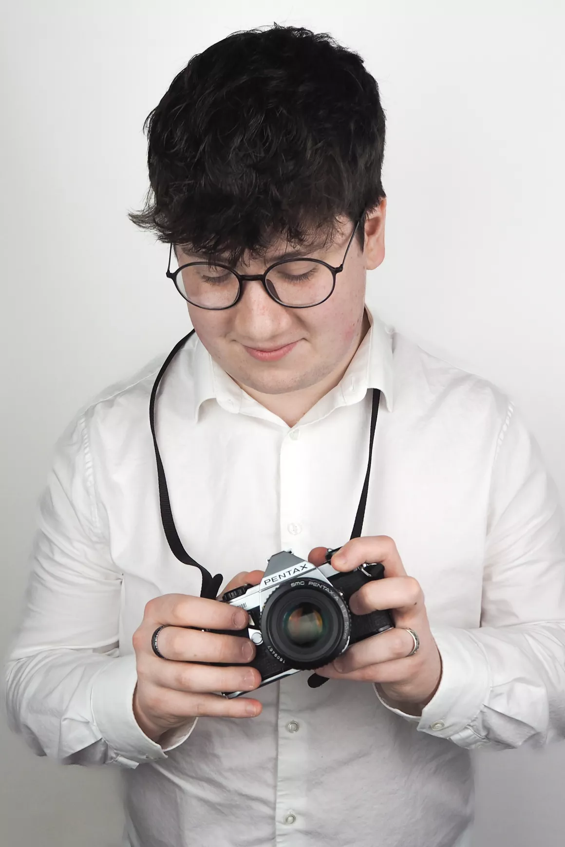 Tom Beale (Consultant) wearing white shirt and black glasses, holding prop which is a camera