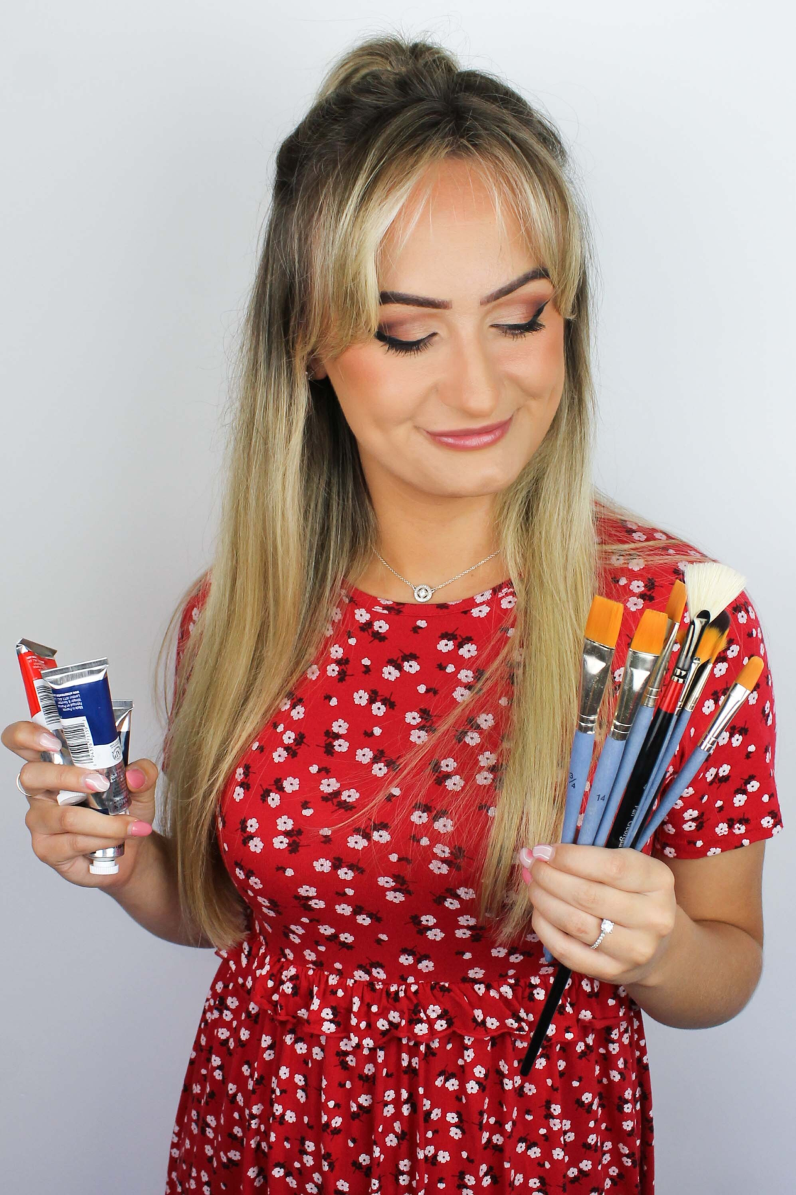 Megan Eves (Design Executive) wearing a red dress holding paint brushes in hand, photo taken at Prime Appointments HQ in Witham 2