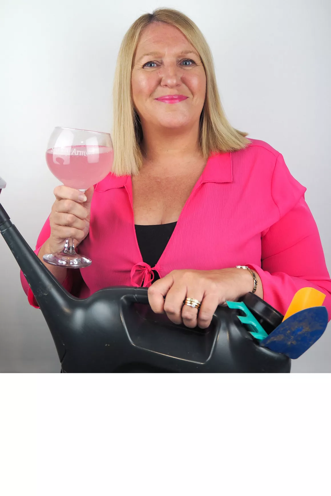 Louise Sutton (accounts) wearing pink top, holding glass of wine and holding gardening props, photo taken at Prime Appointments HQ in Witham 2