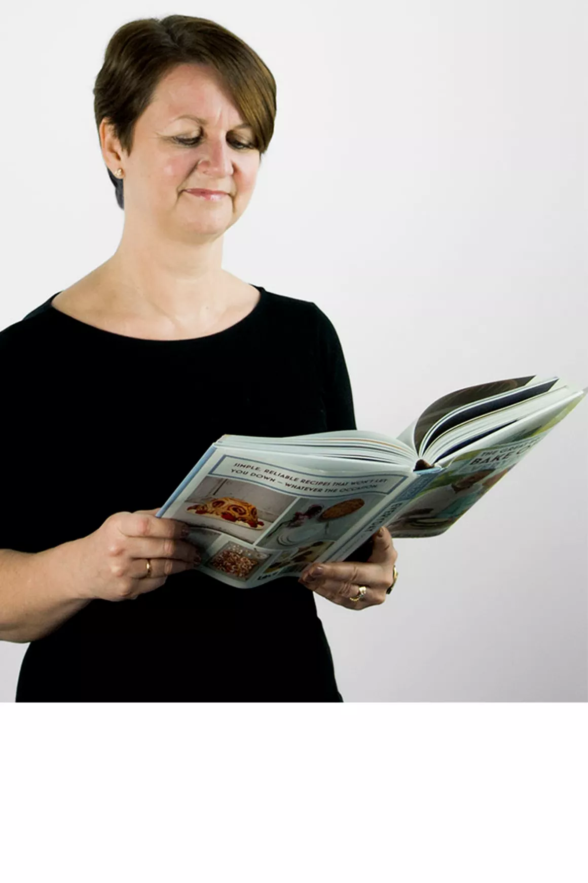 Michelle Kennedy (Senior Office Coordinator) wearing black dress, reading a bakery book, photo taken at Prime Appointments