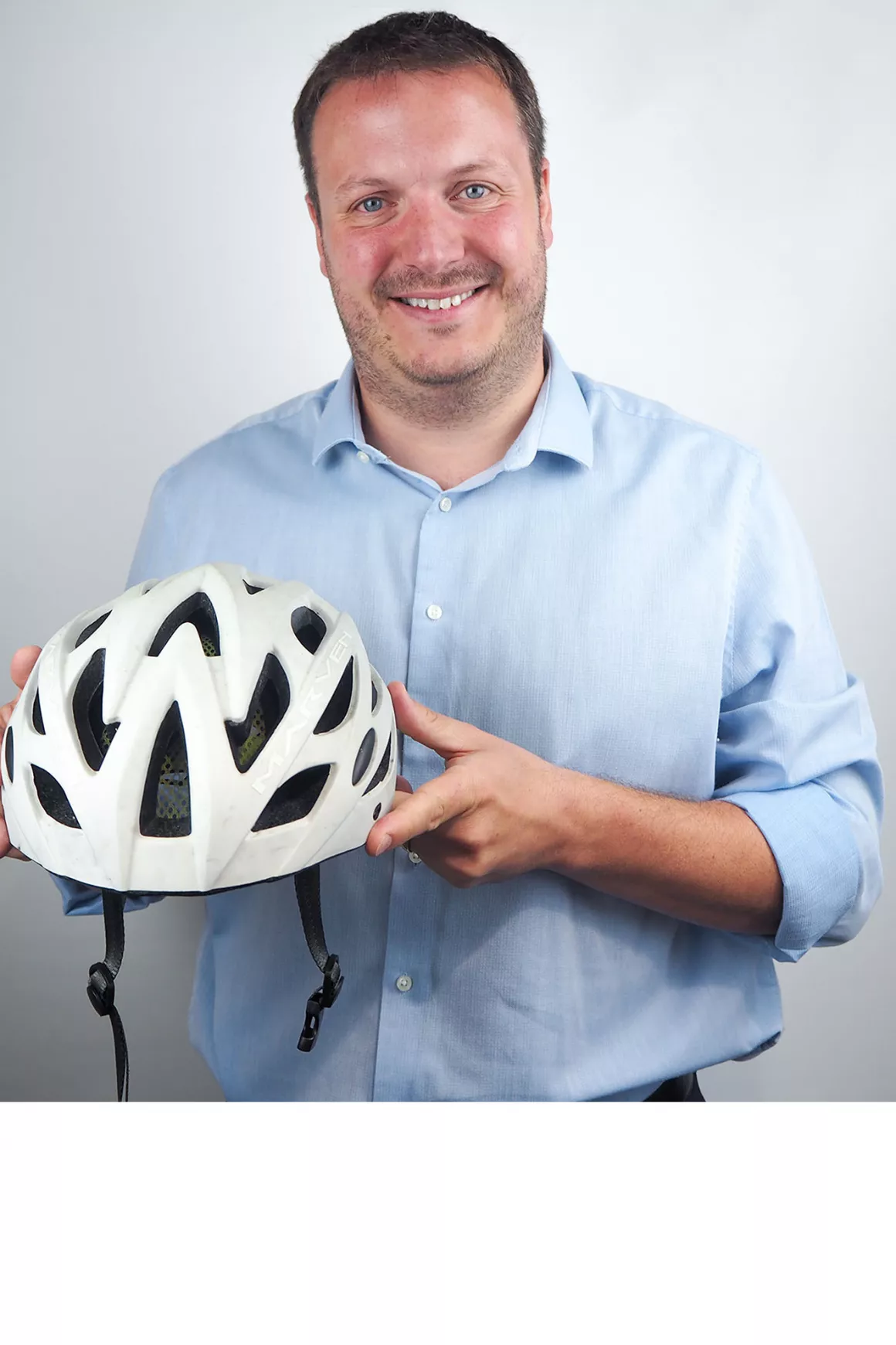 Ross Brown (Senior Consultant) wearing a blue shirt and holding a prop (white cycle helmet), photo with white background