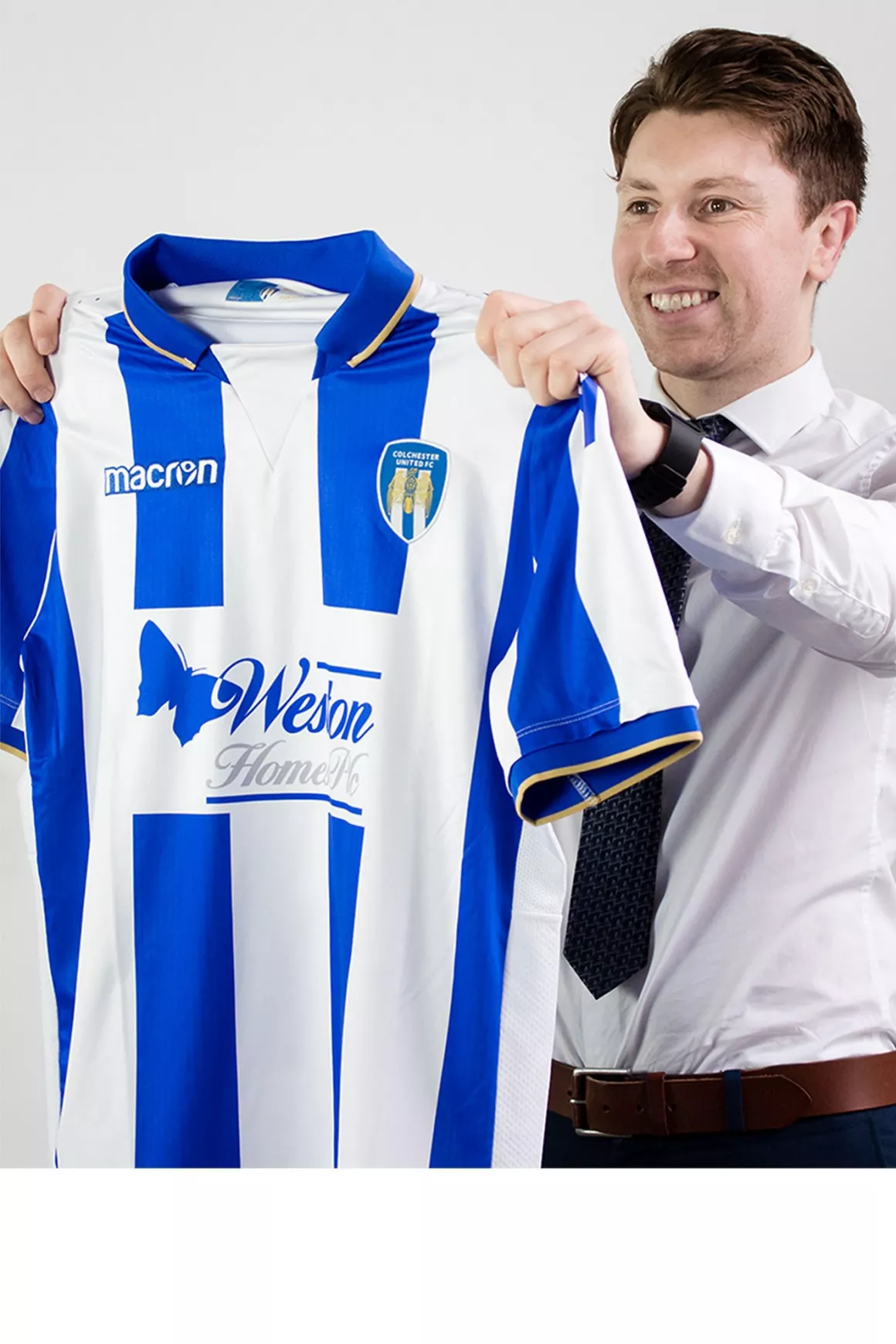 Simon Clark (Senior Consultant) Wearing Shirt and tie, holding a Colchester United Football Top