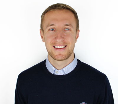 Connor Ellis, Trainee Recruitment Consultant, smiling at camera wearing blue shirt and navy jumper, headshot